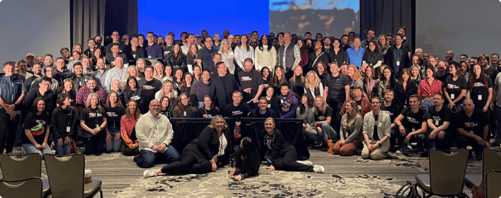 class employees posing in front screen during company-wide event